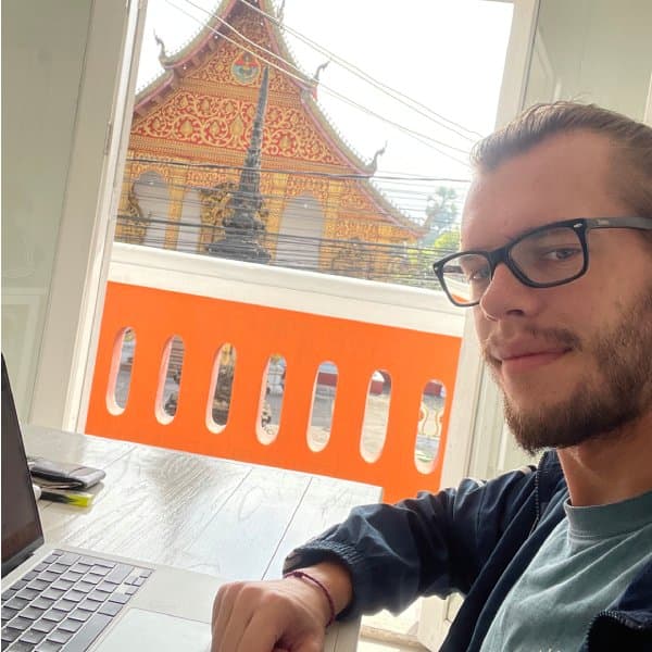 Kirill working on a laptop in front of a temple in Laos